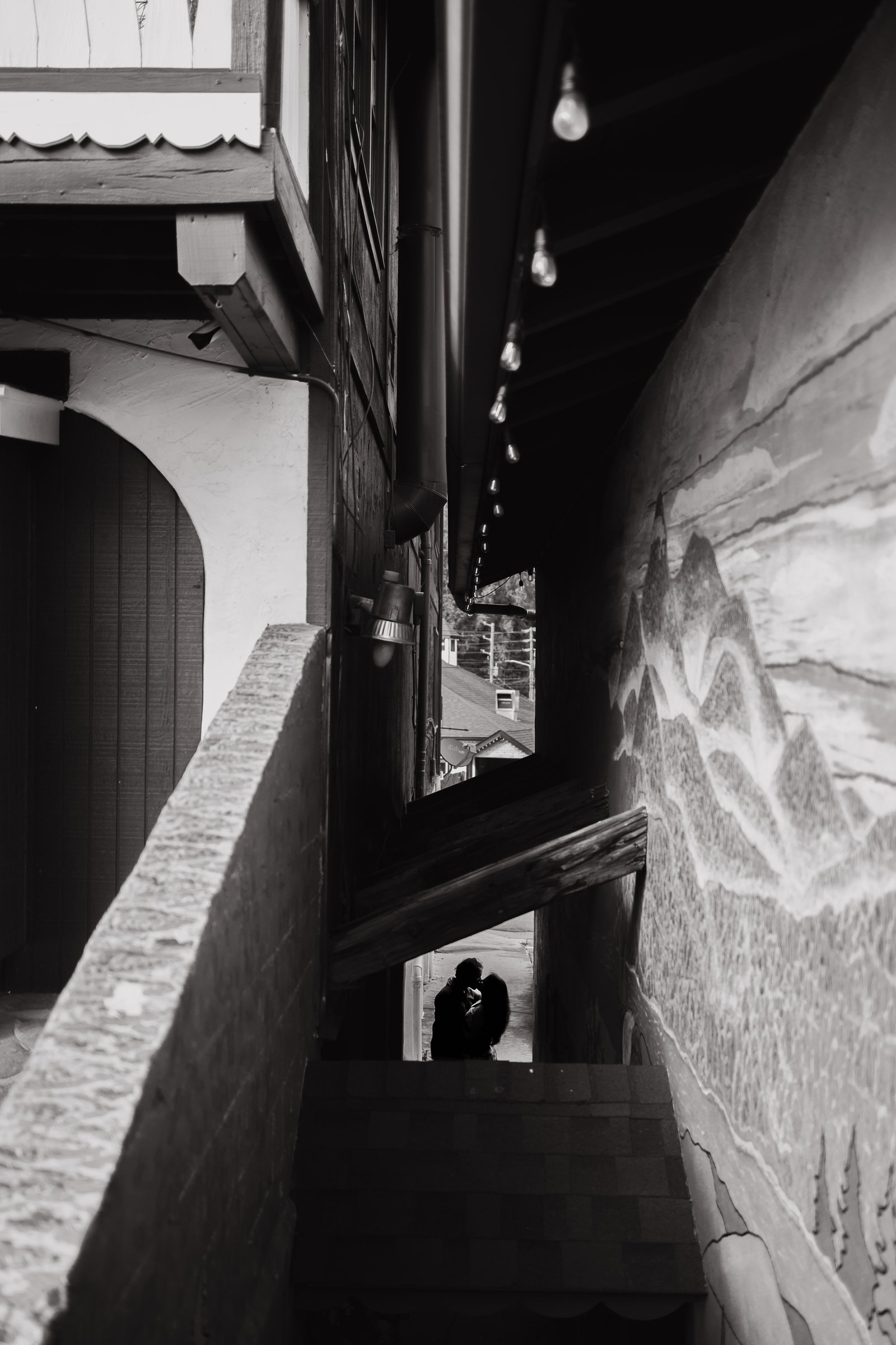 A black and white portrait of the couple beneath a stairway